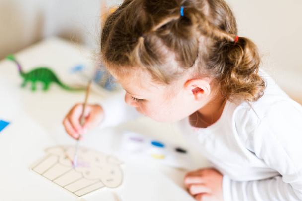 Маленькая девочка рисует за столом дома
. - Фото, изображение