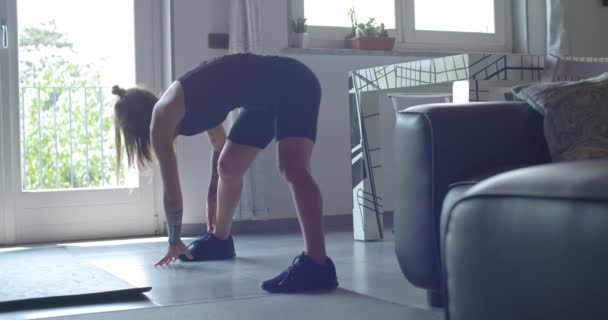 young tattooed woman warming up doing stretching before fitness sport workout at home.Living room domestic training. 4k slow motion video - Πλάνα, βίντεο