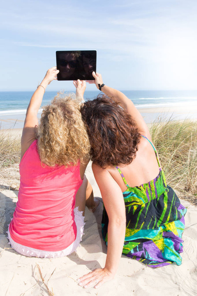 two women in beach vacation take selfie with tablet - 写真・画像