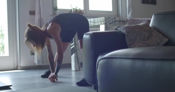 young tattooed woman warming up doing stretching before fitness sport workout at home.Living room domestic training. 4k slow motion video - Metraje, vídeo