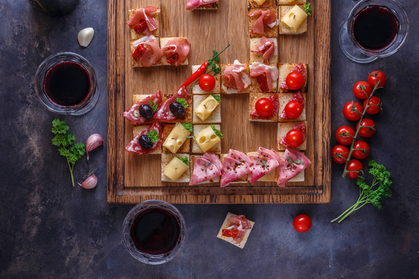 Appetizers asztal olasz tészta elleni rágcsálnivalókkal és borral a szemüvegben. Brushetta vagy autentikus hagyományos spanyol tapas készlet, sajt fajta tábla szürke beton háttér. Felülnézet, lapos fektetés - Fotó, kép