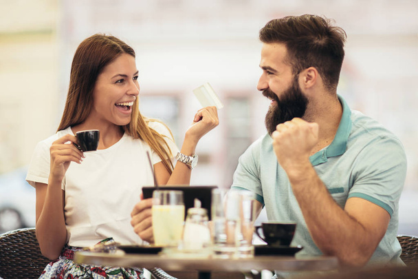 Пара, яка має каву на побаченні, використовує цифровий планшет та кредитну картку для онлайн-покупки
 - Фото, зображення
