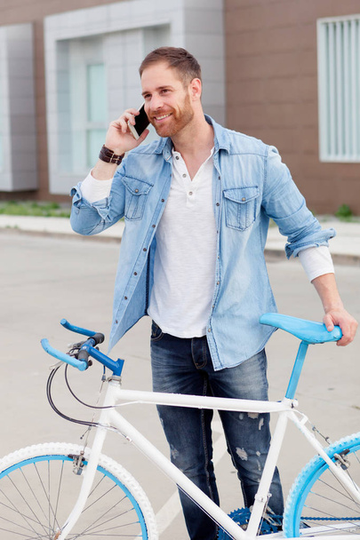 przystojny, młody facet z rowerem, rozmowy przez telefon komórkowy - Zdjęcie, obraz