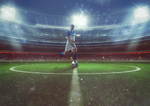 Voetballer raakt de bal uit het middenveld in het stadion - Foto, afbeelding