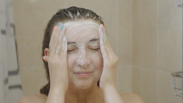 Woman taking a shower. Close-up of attractive brown haired woman lathering her face with soap peeling. - Filmmaterial, Video