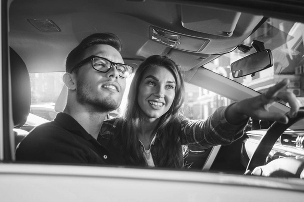Élvezi az utazás. Gyönyörű fiatal pár ül az első utasülés, és mosolyogva, miközben szép ember, autó vezetés. - Fotó, kép