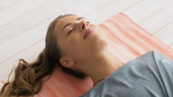 woman doing yoga corpse pose at studio - Imágenes, Vídeo