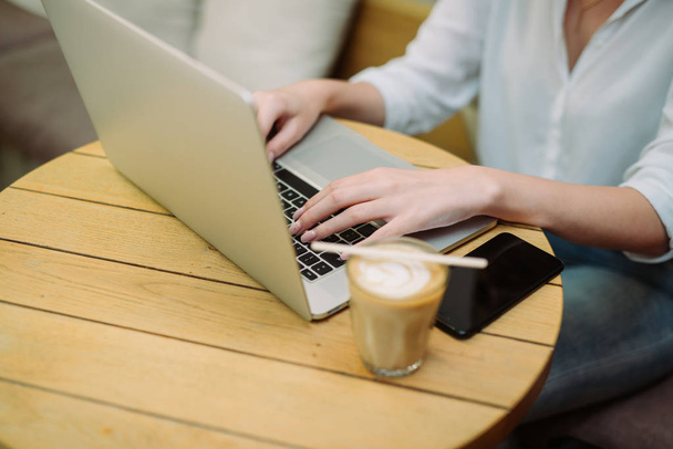 Mädchen im Café-Shop trinkt Kaffee und arbeitet am Laptop - Foto, Bild