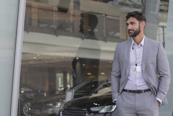 Ritratto fiducioso venditore di auto guardando fuori concessionaria auto showroom
 - Foto, immagini