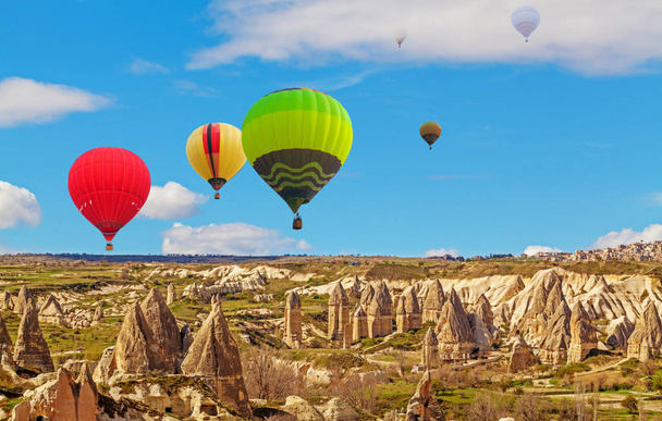 Hot air baloons flying over spectacular stone cliffs in Cappadocia - Photo, Image