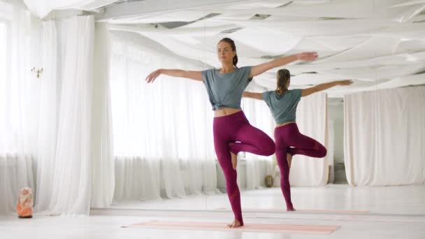 joven mujer haciendo yoga árbol pose en estudio - Imágenes, Vídeo
