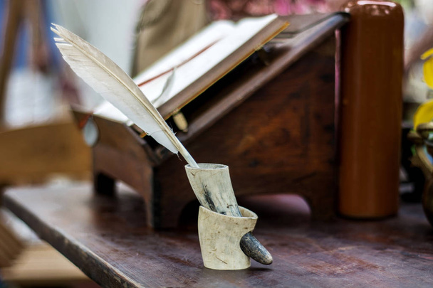 Penna a penna medievale per scrivere in calamaio da corno su scrivania in legno. Concetto di istruzione del Medioevo. Focus ravvicinato e selettivo
 - Foto, immagini