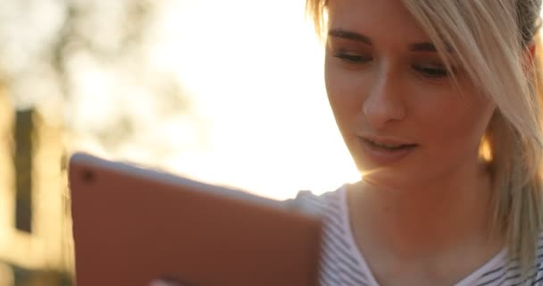 Close-up portrait of young female student using tablet computer in the park. Girl doing online shopping on tablet pc - Materiaali, video