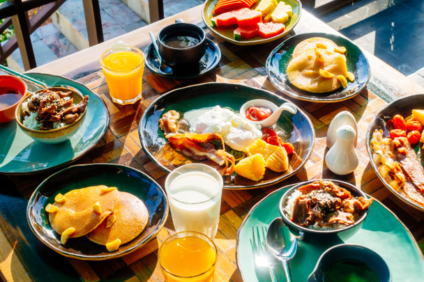 Gezond ontbijt set met ei spek pannenkoeken jus d'orange melk brood koffie en andere op houten tafel - Foto, afbeelding