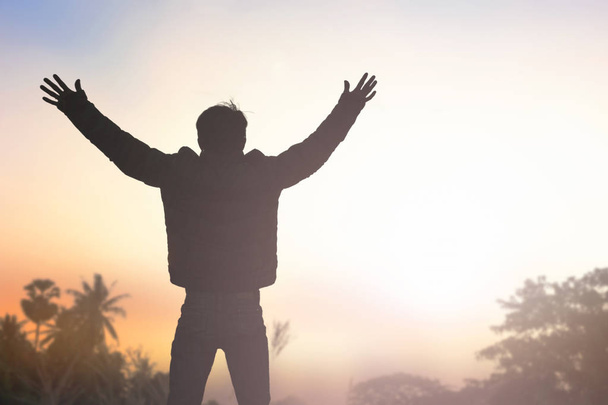 Koncepcja emocjonalny wellness: sylwetka człowieka podniósł ręce w tle zachód słońca meadow - Zdjęcie, obraz