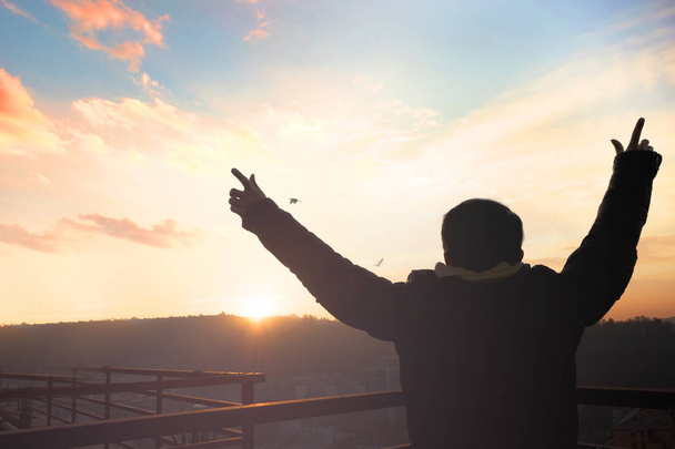 emotionales Wellness-Konzept: Silhouette des Mannes erhobene Hände bei Sonnenuntergang Wiese Hintergrund - Foto, Bild