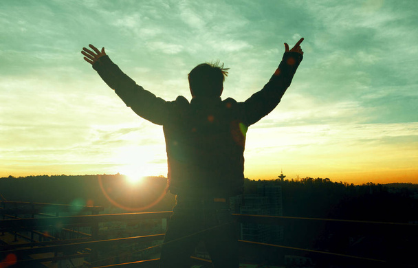 Эмоциональная концепция хорошего самочувствия: силуэт человека, поднявшего руки на фоне луга заката
 - Фото, изображение