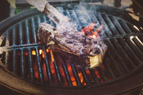 Delicious grilled beef steak on a barbecue grill, close-up. Blade of beef on an open fire in the smoke - Photo, Image