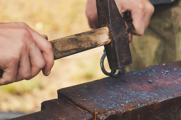 Der Schmied schmiedete traditionelle Hammerschläge aus Eisen. Schmiedehammer aus Metallkonstruktionen im Freien in der Natur. - Foto, Bild