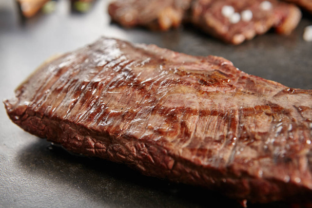 Hot Grilled Whole Flank Steak on Black Stone Background. Fresh Juicy Medium Rare Beef Grillsteak. Barbecue Meat Close Up - Foto, Imagem