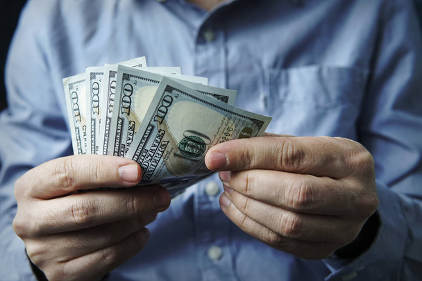Cash in hands. Profits, savings. Stack of dollars. Man counting money. Dollars in man's hands. A man in business clothes with dollars. Success, motivation, financial flows, wealth. Stack of dollars. - Photo, Image