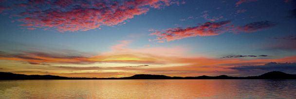 Un llamativo color rosa inspirador nublado amanecer mar sobre el agua de mar con reflejos de agua
 - Foto, imagen