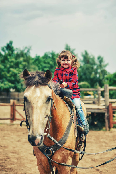 Una niña está entrenada para montar a caballo.
 - Foto, Imagen