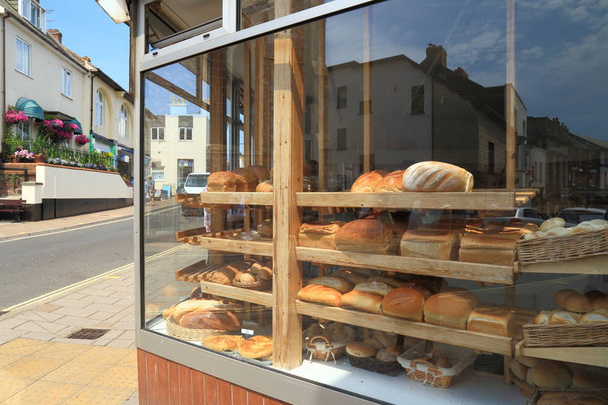 Police plné čerstvě upečený bochníků chleba zobrazených v okně obchod ve městě Sidmouth, East Devon - Fotografie, Obrázek