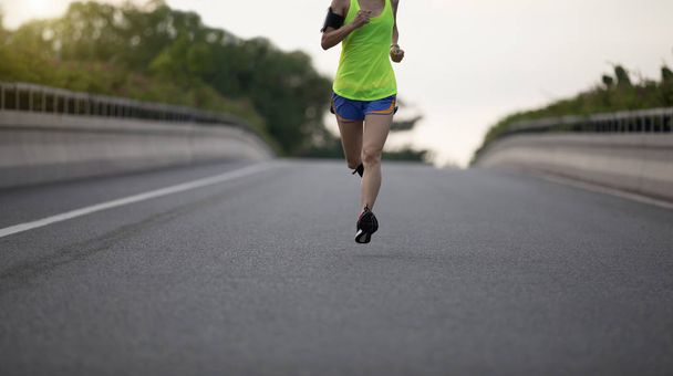 Young fitness woman running on city road - Photo, Image
