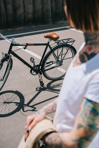 partial view of tattooed woman standing near bicycle at street - Photo, Image