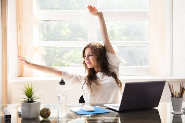 Jovem empresária feliz esticando seus braços no escritório
 - Foto, Imagem
