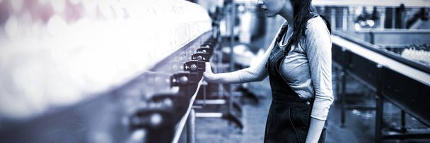 Працівник жіночої фабрики оглядає виробничу лінію на фабриці з виробництва напоїв
 - Фото, зображення