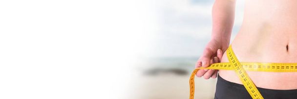 Digital composite of Woman measuring weight with measuring tape on waist on Summer beach with transition - Фото, изображение