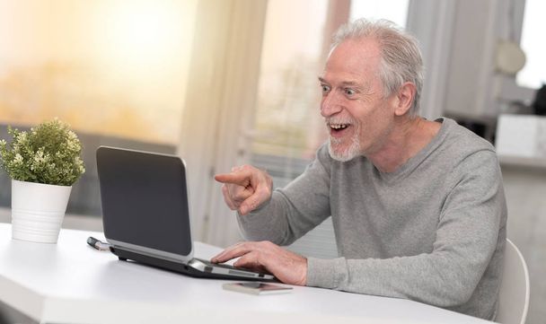 glücklich reifer Mann mit einer erstaunlichen Überraschung auf Laptop, Lichteffekt - Foto, Bild