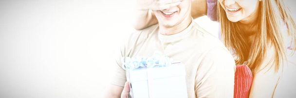 Smiling woman giving a present to her boyfriend in the livingroom - Foto, Imagem