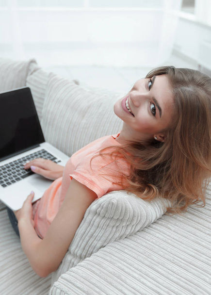 portret young woman working with laptop sitting on sofa - Фото, изображение