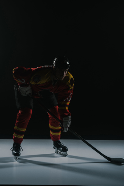 vue pleine longueur du sportif en vêtements de sport de protection jouant au hockey sur glace sur noir
 - Photo, image