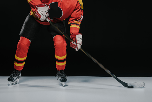recortado tiro de deportista con palo de hockey jugando hockey sobre hielo en negro
 - Foto, Imagen