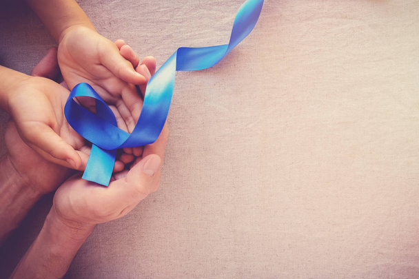 Human hands holding bright blue ribbon. World cancer day. - Foto, afbeelding