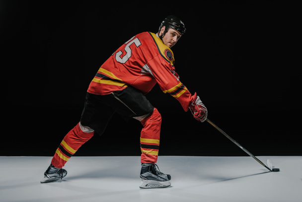 young professional sportsman playing ice hockey on black   - Foto, imagen