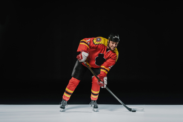 full length view of young professional sportsman playing ice hockey on black  - Photo, Image