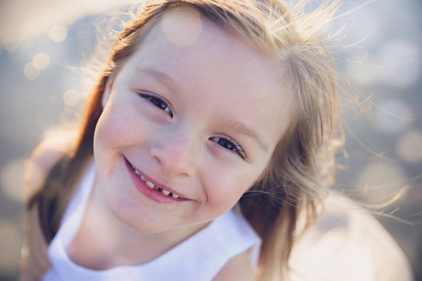 Happy little girl smiling, soft focus, fairy light toning background - Valokuva, kuva