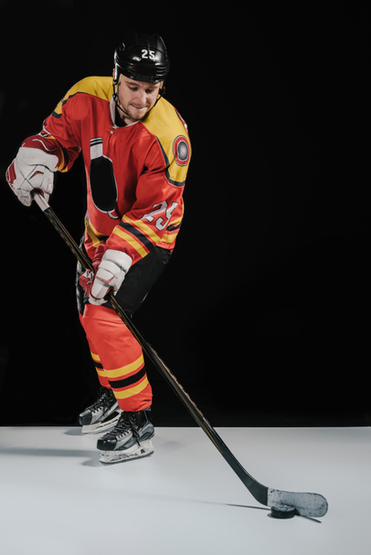 full length view of professional sportsman in skates playing hockey on black - Photo, Image