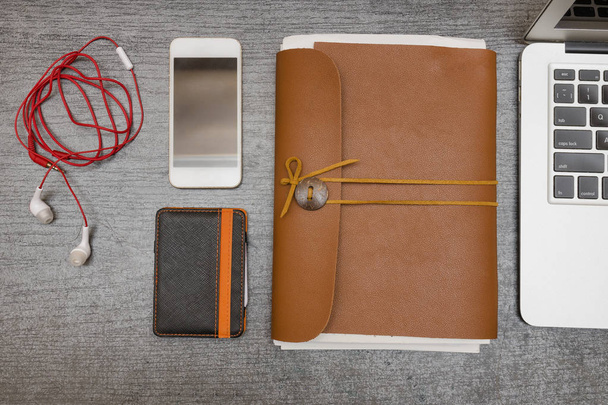 Smart phone, wallet, part keyboard, headphones and a leather notebook on a black table. Top view - Φωτογραφία, εικόνα