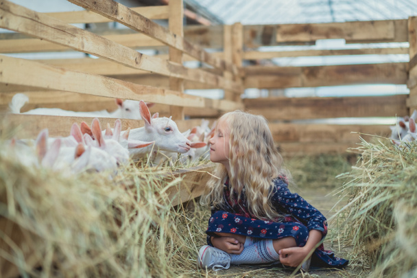 vista lateral del niño que va a besar cabra en la granja
  - Foto, Imagen
