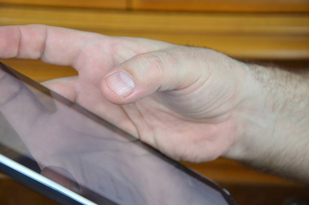 Κοντινό πλάνο ενός tablet και επανδρώνει το χέρι σε μια θέση σε μια οθόνη αφής - Φωτογραφία, εικόνα