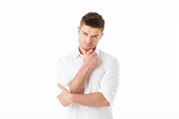 Portrait of a pensive young man looking at camera isolated over white background - Φωτογραφία, εικόνα