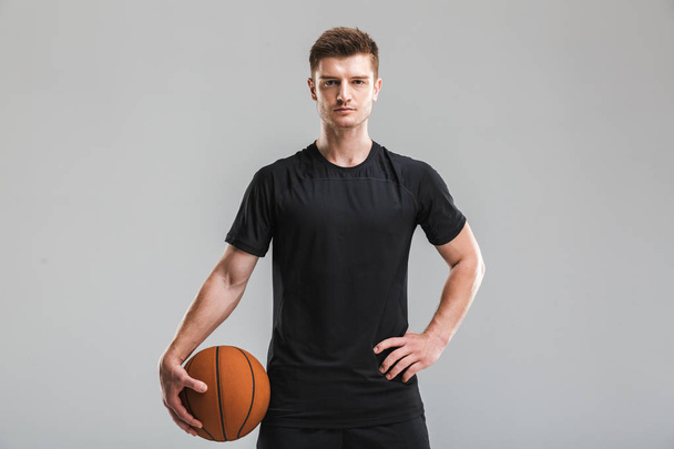 Keskittyneen nuoren urheilijan muotokuva, jolla on harmaalla pohjalla eristetty koripallo
 - Valokuva, kuva