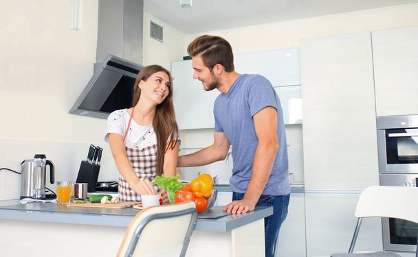Portrait of happy young couple cooking together in the kitchen at home - Foto, imagen