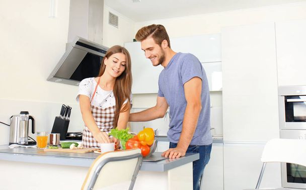 Portrait of happy young couple cooking together in the kitchen at home - Foto, Imagen